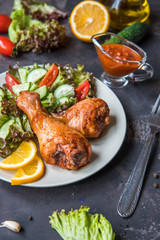 Fried chicken legs and fresh salad on a dark background