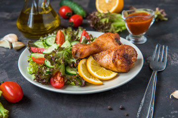 Fried chicken legs and fresh salad on a dark background