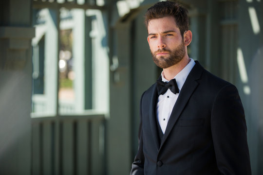 Sharply dressed groom in black tuxedo looking polished, chic, dapper, and dignified