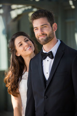 Fun portrait of handsome newlywed groom posing while wife makes him laugh