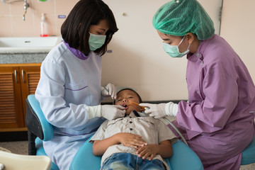 Obraz na płótnie Canvas Dentist holding a dental tool. Checking the teeth to the boy lying in the dental chair in a hospital..