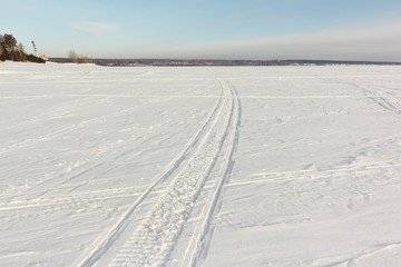 Traces from a snowmobile on a snow surface of the river, Ob Reservoir, Russia
