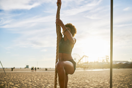 african american woman climbing rope on beach