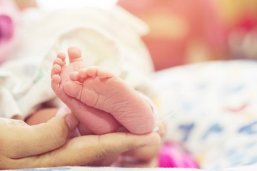 Close Up newborn infant Baby feet in mother hands. Baby's feet on female Shaped hands Mom and her Child. Beautiful conceptual image of Maternity