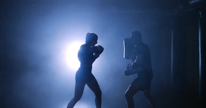 Silhouettes of a boxer and coach in a dark smoky room