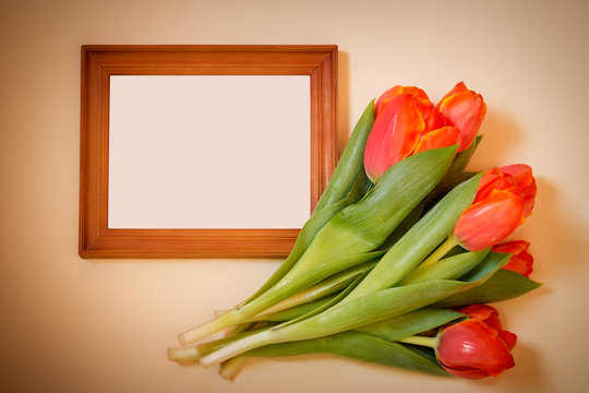 Tulips with blank picture frame on beige background