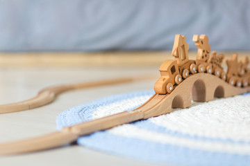 Wooden toy train on railroad with wooden bridge on the floor of a children's room.