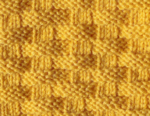 Knitting from woolen threads of a beautiful pattern with a braid pattern. The texture of acrylic is orange, the sample is made by handwork.