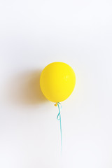 The yellow balloon against the background of a white wall