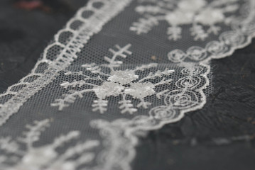 White Lace Embroidered Border on Dark Surface. Lace Texture Background on Dark Gray Board.