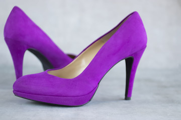 Violet velvet  shoes heels on gray background.