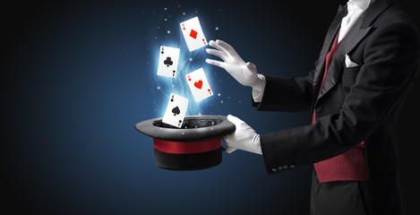 Magician making trick with wand and playing cards