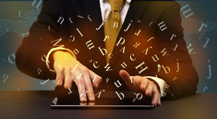 Man typing in formal clothing and letters around