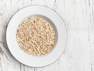 Oatmeal, rolled oats on white wooden table. Porridge oats