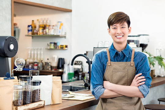 Cheerful young Asian man entrepreneur in coffee shop