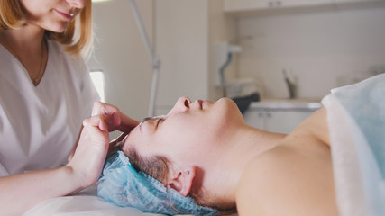Obraz na płótnie Canvas Woman doctor performes cosmetic procedure - mask facial massage at spa salon skincare