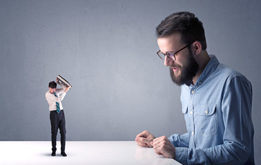 Young businessman fighting with miniature businessman