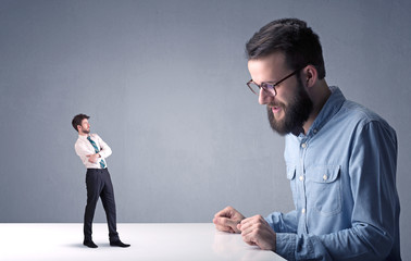 Young businessman fighting with miniature businessman