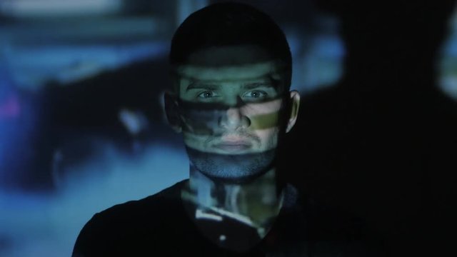 Close up of a young man watching a video or film on TV or a computer monitor. Reflection on his face. Timelapce