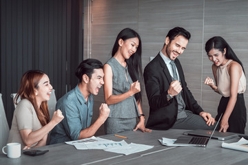 Fototapeta premium Happy business team celebrate success looking at laptop in the office. Successful, winners excited of victory at meeting. 