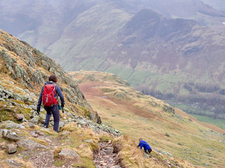 Fototapeta na wymiar A hiker and their dog walking in the mountains of the English Lake District.