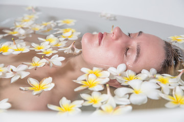 Obraz na płótnie Canvas Woman relaxing in bath with tropical flowers organic skin care luxury spa hotel