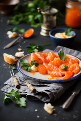 Smoked salmon slices with salted salmon caviar decorated with fresh parsley leaves