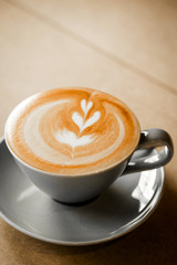 cup of coffee with heart pattern in a white cup on wooden background