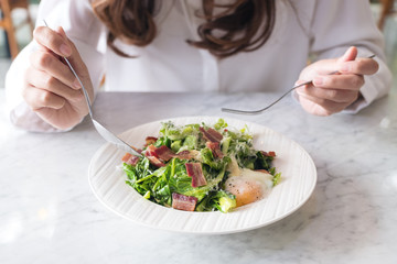A woman enjoy eating warm salad on table in the restaurant