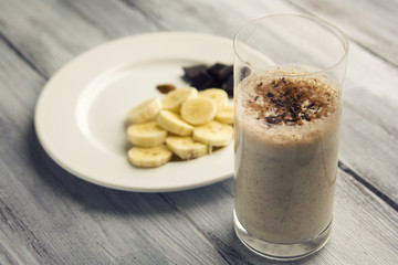 Banana chocolate smoothie with a dash of cinnamon. A glass of milk smoothie sprinkled with chocolate. Healthy breakfast. Lacto vegetarian dish.