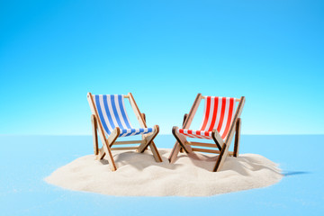 Two sun loungers on a sandy island, copy space