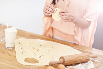 Young woman trying to make pierogi in kitchen