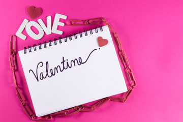 Valentine's day love letter with notebook on pink paper background with copy space