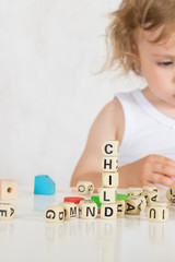 Small girl composes words from letters. Closeup