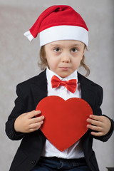 Boy of four years in Santa's hat and with red heart box.