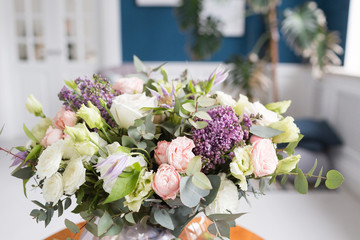 Sunny spring morning in living room. Beautiful luxury bouquet of mixed flowers in glass vase on wooden table. the work of the proffesional florist at a flower shop.