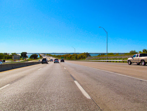 Panorama of highway towards Dallas, Texas, USA.
View of the asphalt road, lake, bridge and buildings of center of Dallas in a bright sunny day with a clear blue sky background.