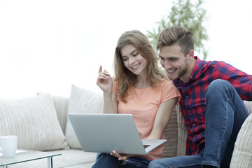 young man with his girlfriend watching a TV show on the laptop sitting in the living room