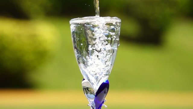 Drinking water.
Pure water dropping in crystal glass till water overflowing ,HD slow motion and blurred background.