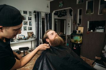 handsome young bearded guy sitting in an armchair in a beauty salon