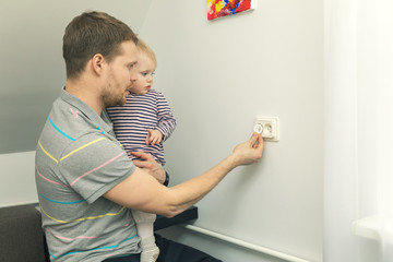 child safety at home. father takes care to protect kid from electrical injury