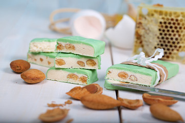 Almond turron covered by pistachio chocolate on a wooden surface.
