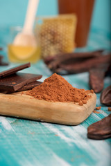 Carob pods and powder on a wooden surface.