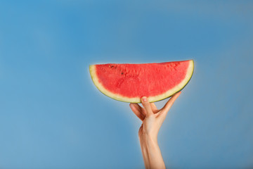 Young lady keeps a slice of water melon on a blue background.