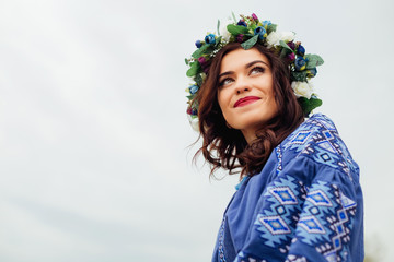 close-up of a girl with a wreath of flowers on her head and beautiful makeup that looks into the...