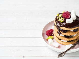 A sweet dessert of a chocolate cookie raspberry and marshmallow on a light table.