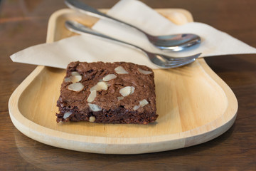 Almond dark chocolate brownie on wood dish.