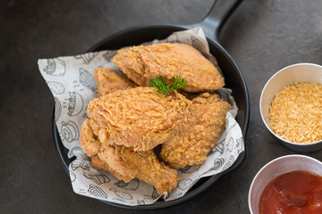 Delicious fried chicken wings on the small pan with sauce. Focus on the parsley on top.