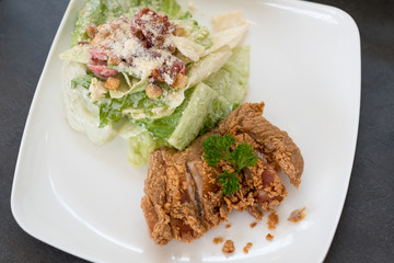 Fried chicken salad with salad cream, bacon, cheese on top.