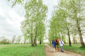 Fototapeta premium a guy and his girlfriend in festive clothes walk around the village and keep a horse behind the bridle